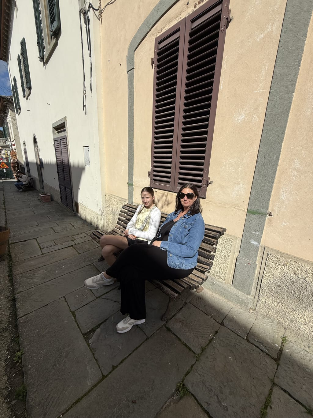 Maia and Anca on a bench on a beautiful street.