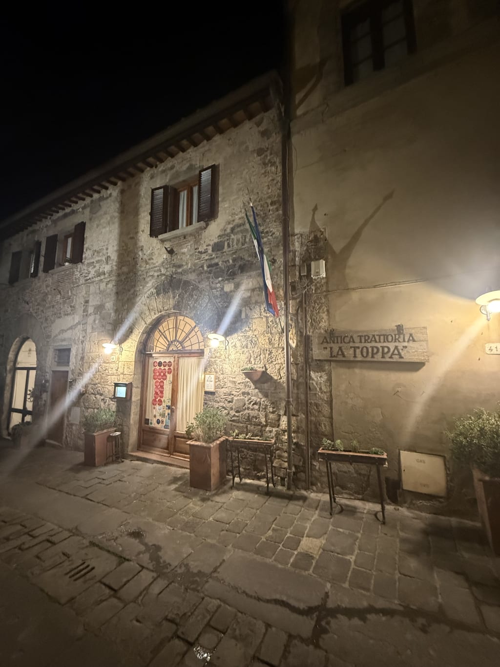 A rustic stone building at night with a sign reading "Antica Trattoria La Toppa." This is where we had our best meal in Tuscany.