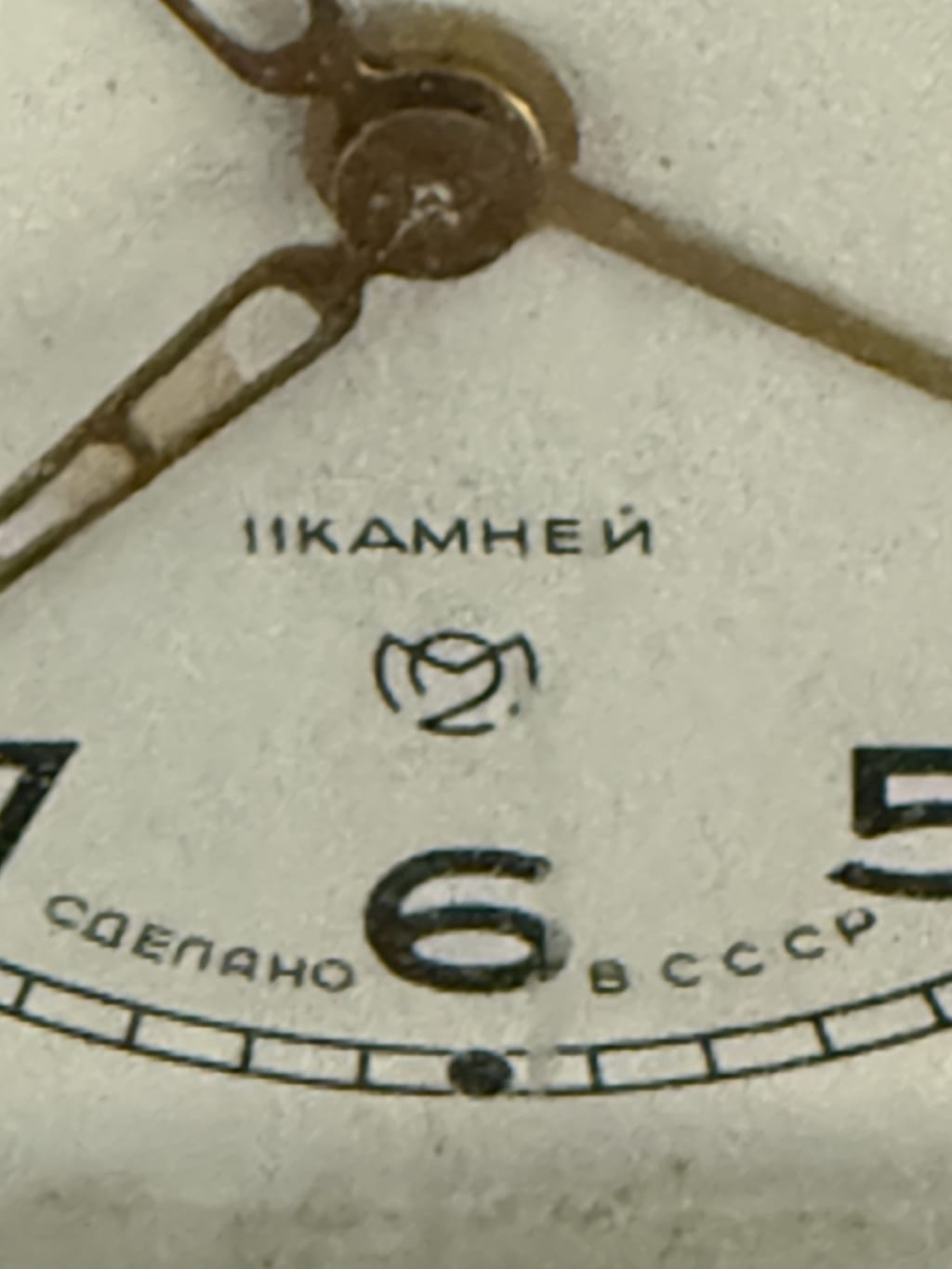 Close-up of a vintage watch face with Cyrillic text and metal hands.