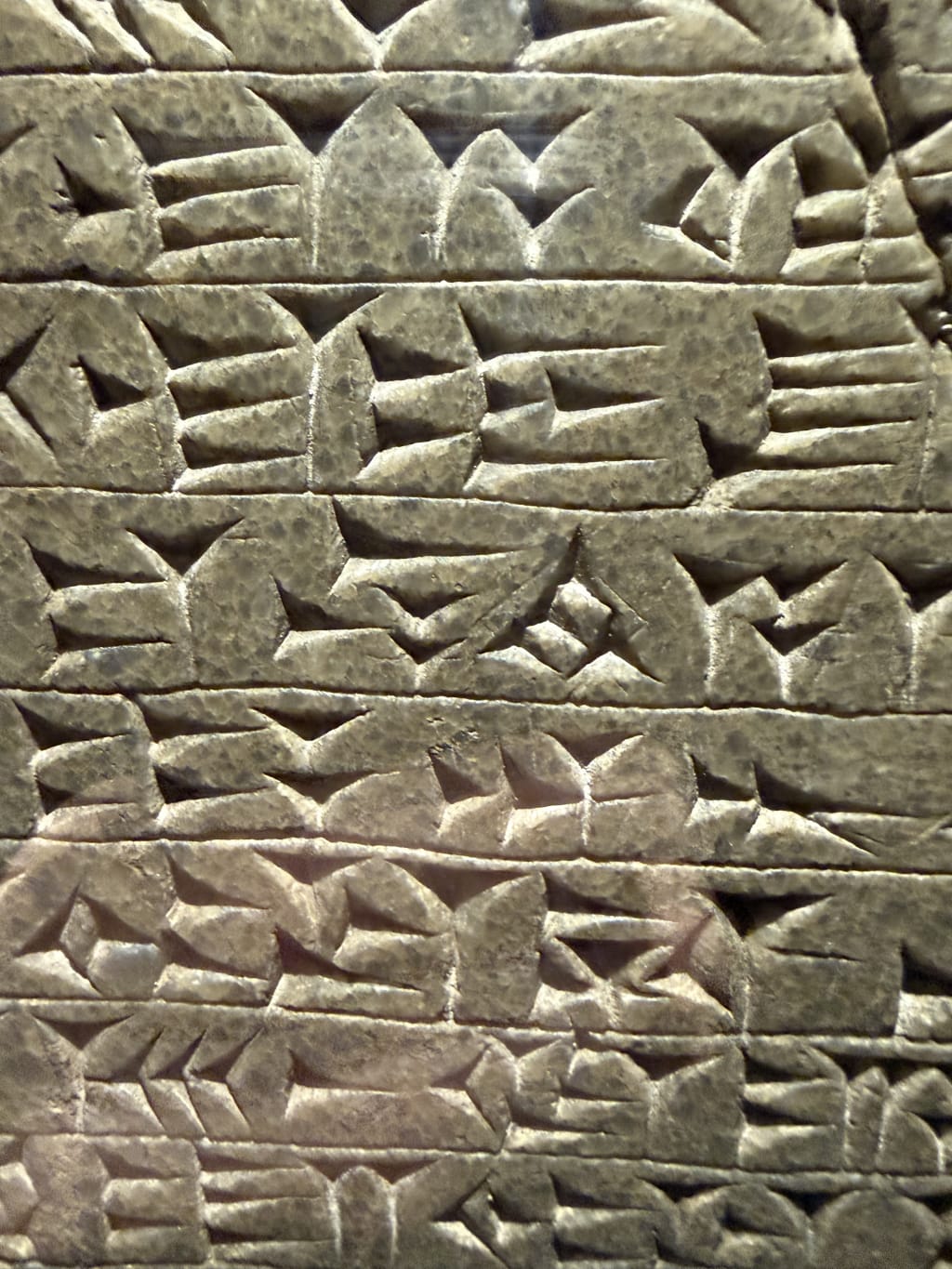 Close-up of ancient cuneiform script carved in stone tablet with wedge-shaped marks.