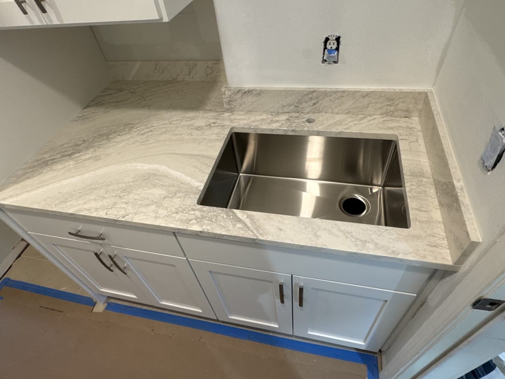 Newly installed white marble countertop with an undermount stainless steel kitchen sink.