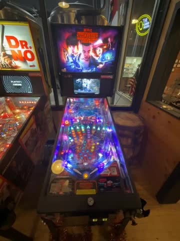 This is a pinball machine themed around "Stranger Things," brightly lit and placed indoors.