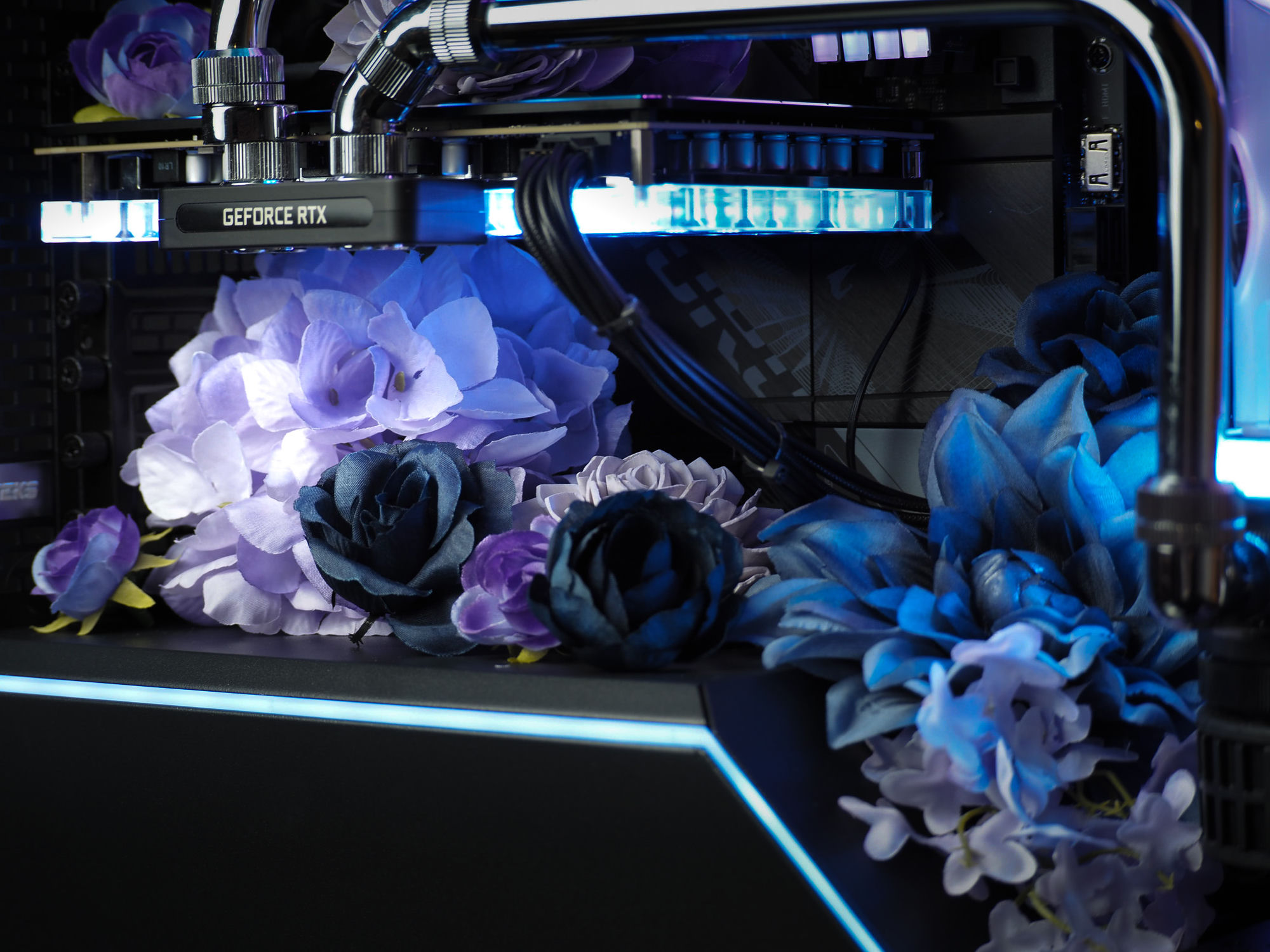 A bouquet of purple and blue silk blooms nestled under the graphics card
