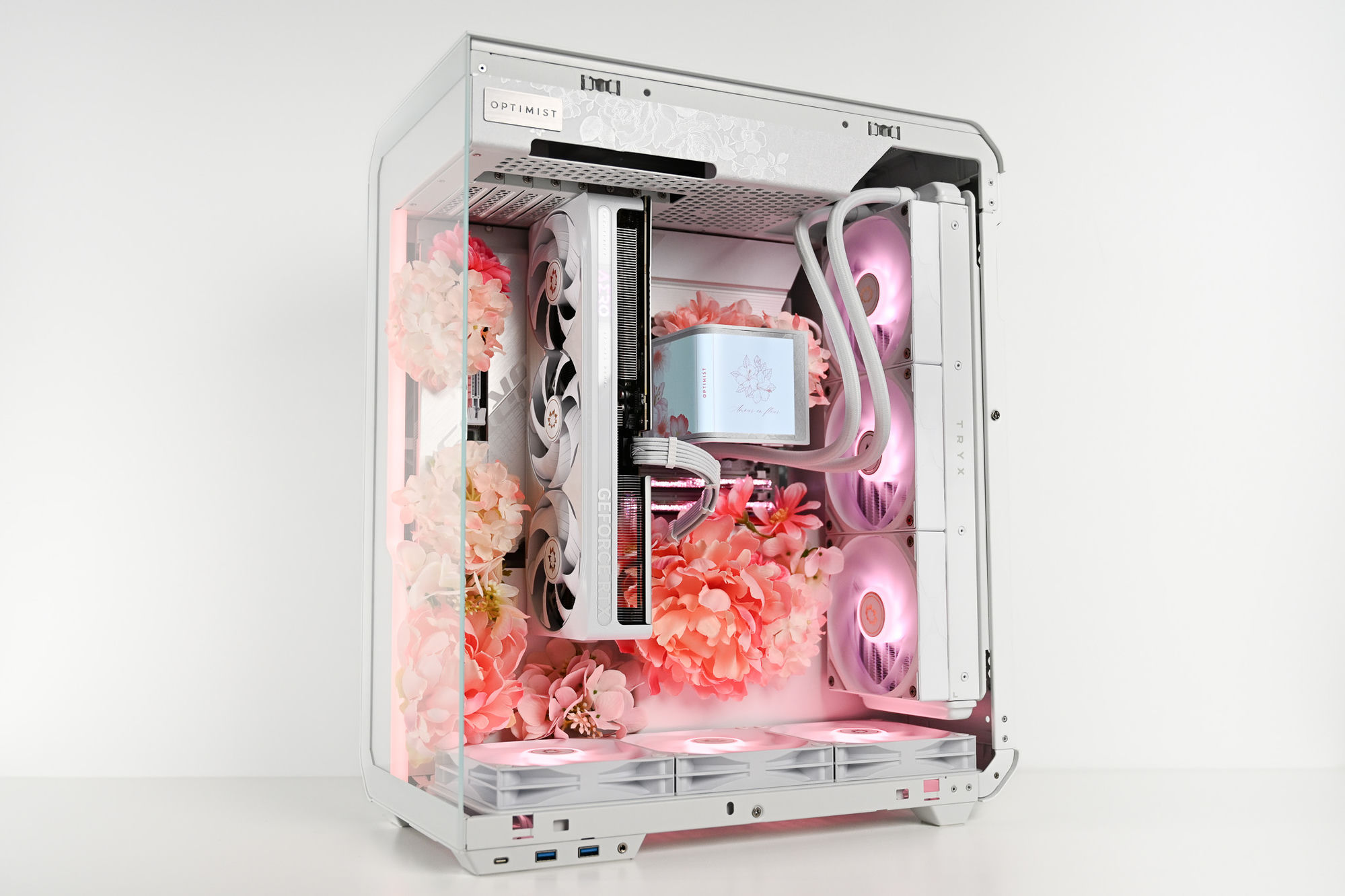 Fleur beauty shot — a white TRYX tower packed with pink blooms, floral-etched top panel, AERO GPU and the Amour en fleur screen