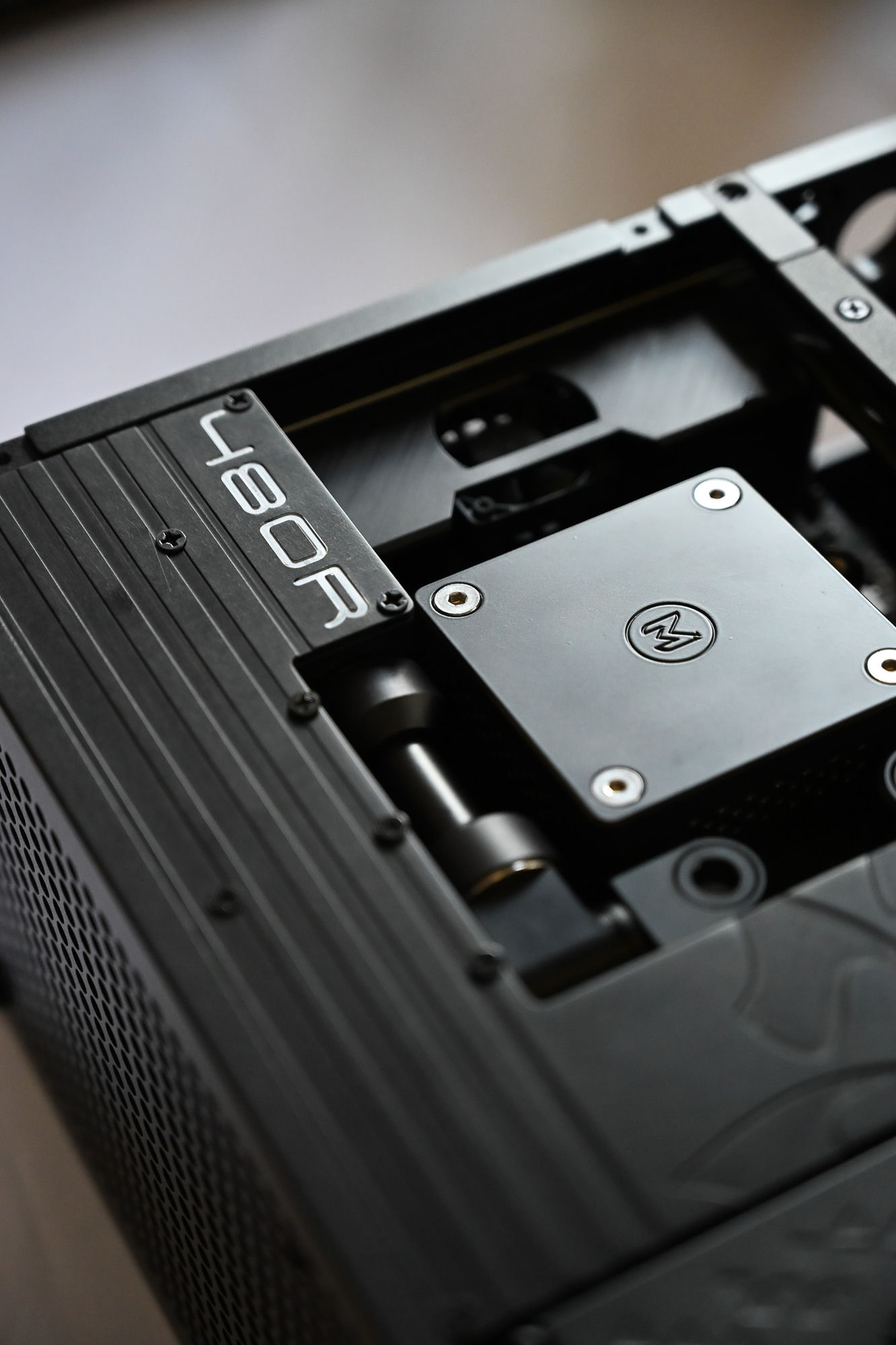 The 480R side panel beside an early Optimist water block, hardline fittings and reservoir on the bench