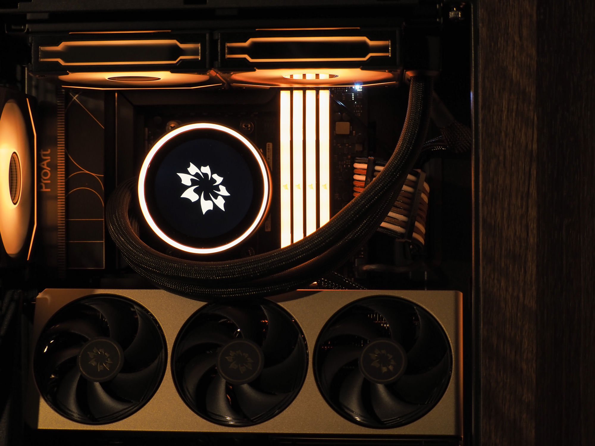 The refreshed Nocturne interior — Kraken Elite, brass MSI Inspire card, glowing memory and brown cabling under warm light
