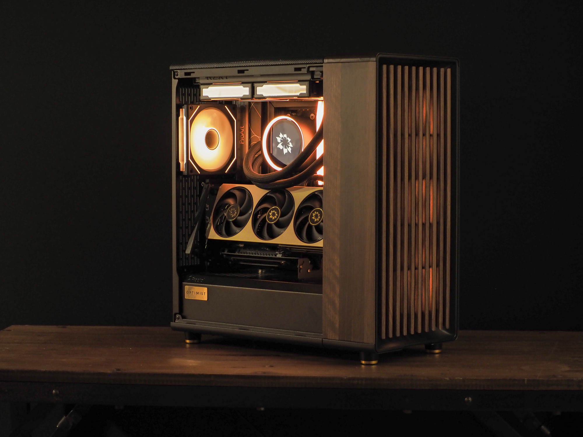 The refreshed Nocturne — a warm-lit ProArt build on the RTX 50-series platform, walnut side panel, on a wooden desk