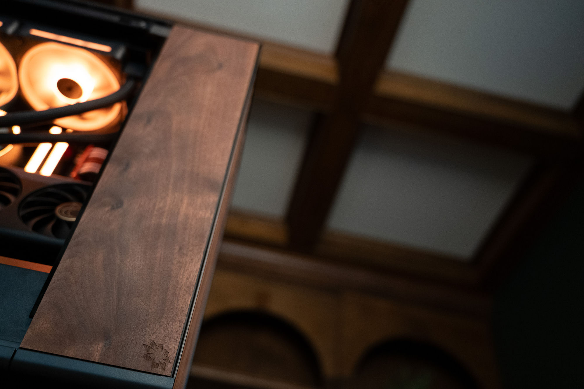 The 2026 Nocturne's solid hardwood side panel, laser-etched with the Optimist flower emblem, warm light spilling from the interior