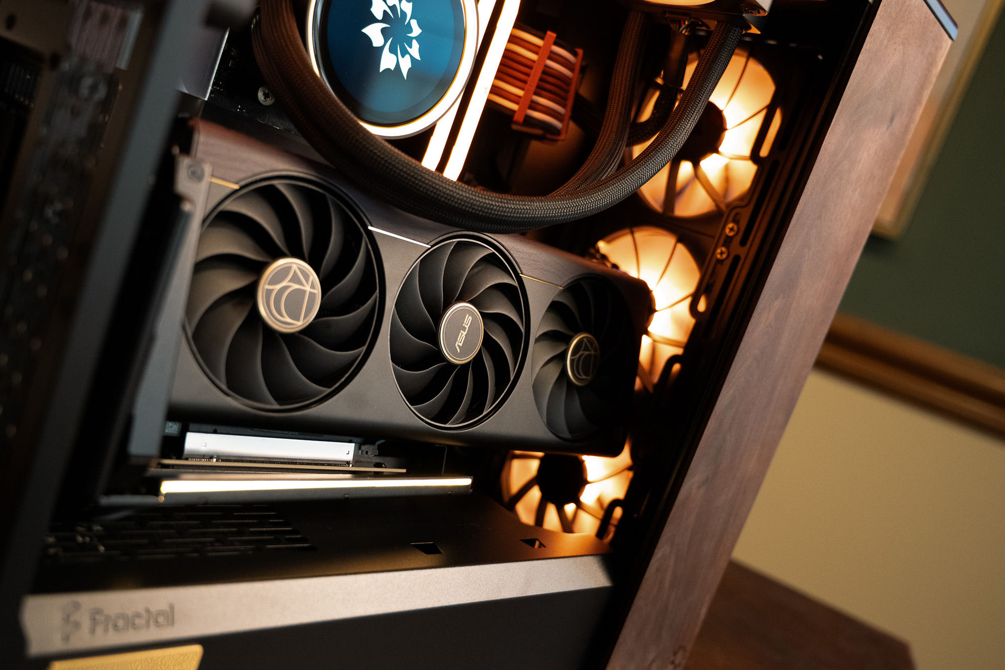 The Nocturne interior — flower-emblem pump, brown-and-black cabling and Corsair fans glowing warm, above the graphics card