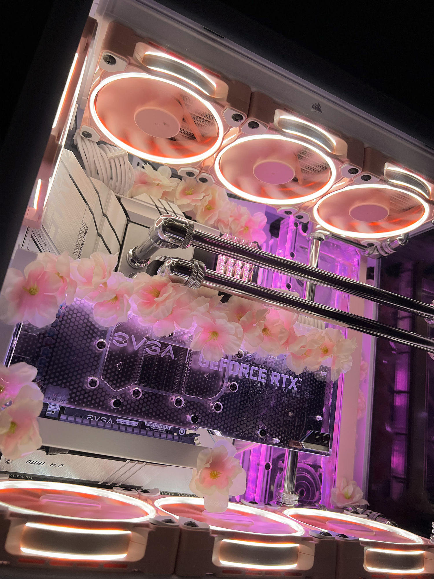 The Sakura V2 — cherry blossoms threaded through a white hardline water-cooled build, lit from soft pink into purple, over an EVGA GeForce RTX block