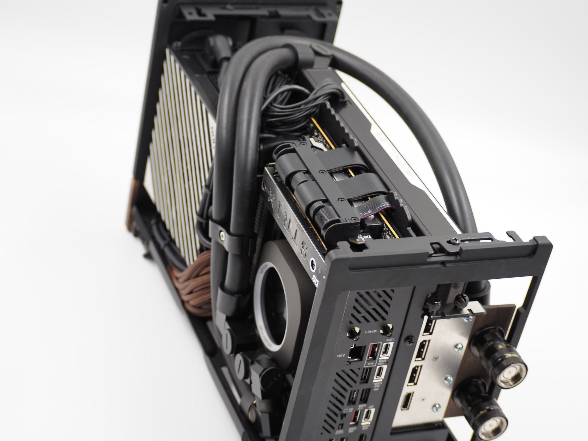 Inside the SFF unit — quick-disconnect couplers on the coolant lines beside the rear I/O (Wi-Fi 7, 2.5G, DisplayPort)