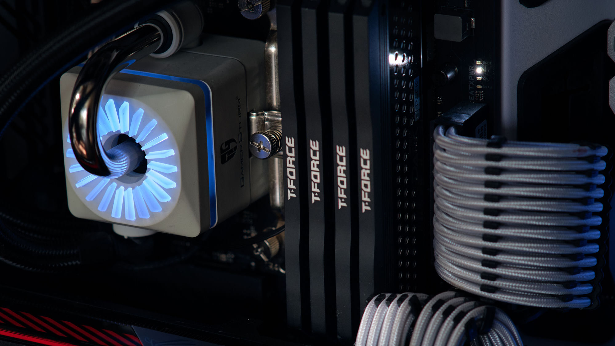 A close-up of a white liquid-cooler pump lit with a blue ring, beside T-FORCE memory and white sleeved cables