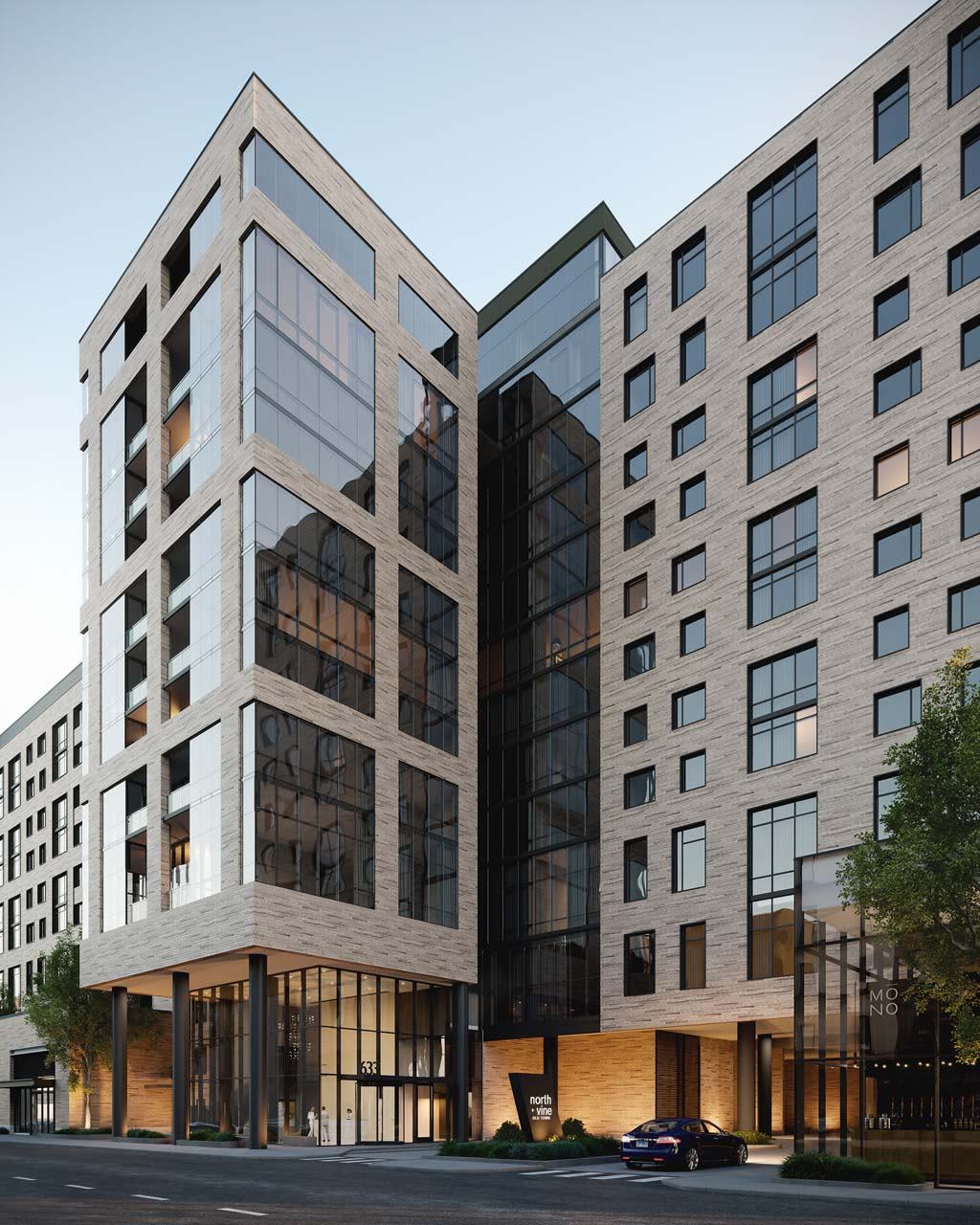 Contemporary multi-story residential building with light brick facade, large windows, and illuminated ground-floor entrance with black framing.