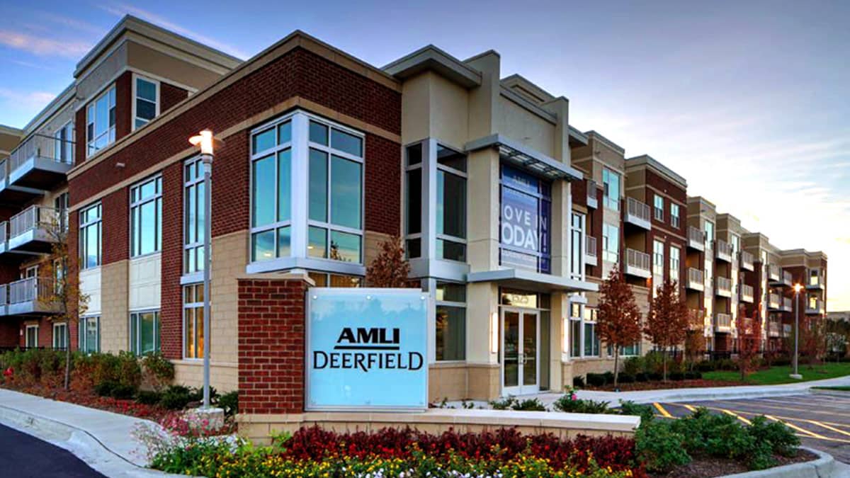Modern apartment building exterior with red brick, large windows, and landscaped entrance in Deerfield.
