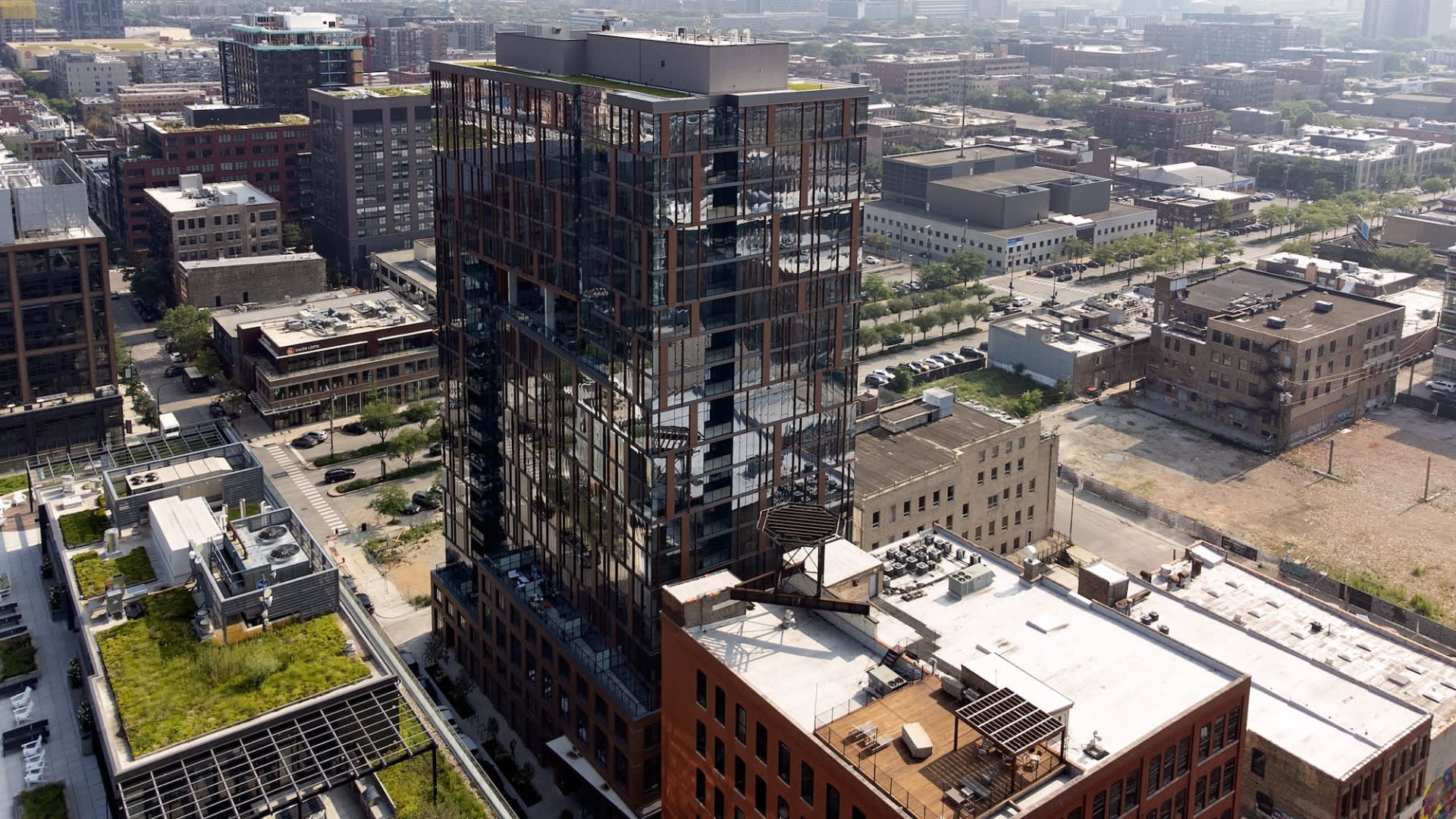 Aerial view of modern high-rise residential building with floor-to-ceiling windows overlooking Chicago cityscape and surrounding buildings.