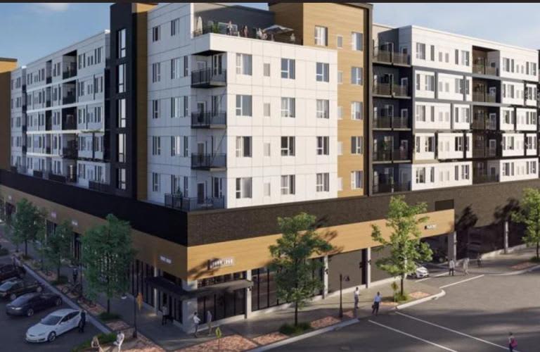 Modern apartment building with white and tan facade, ground-level retail spaces, and street-level pedestrian area in Des Plaines.