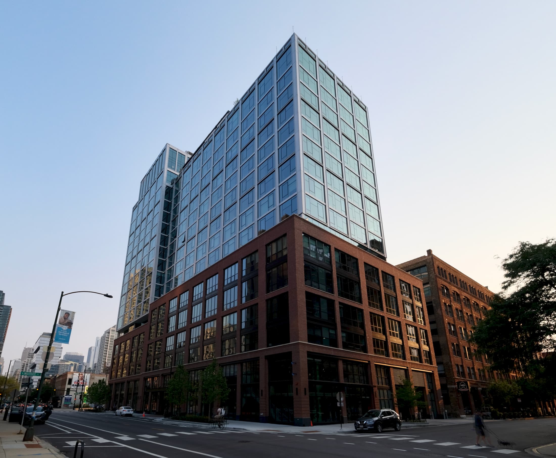 Modern residential building with blue-glass upper tower and red-brick lower levels on a Chicago street corner.