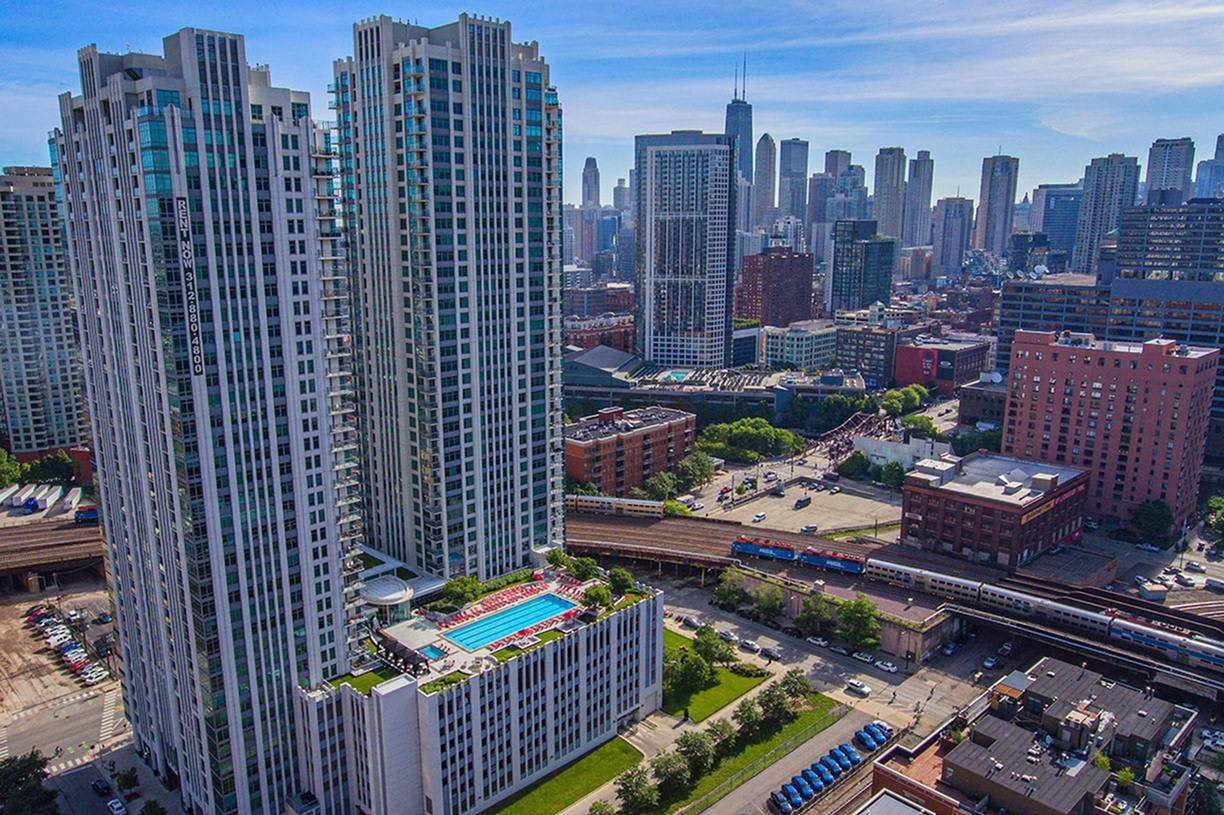 Modern residential high-rise towers with rooftop swimming pool overlooking Chicago skyline and downtown buildings.