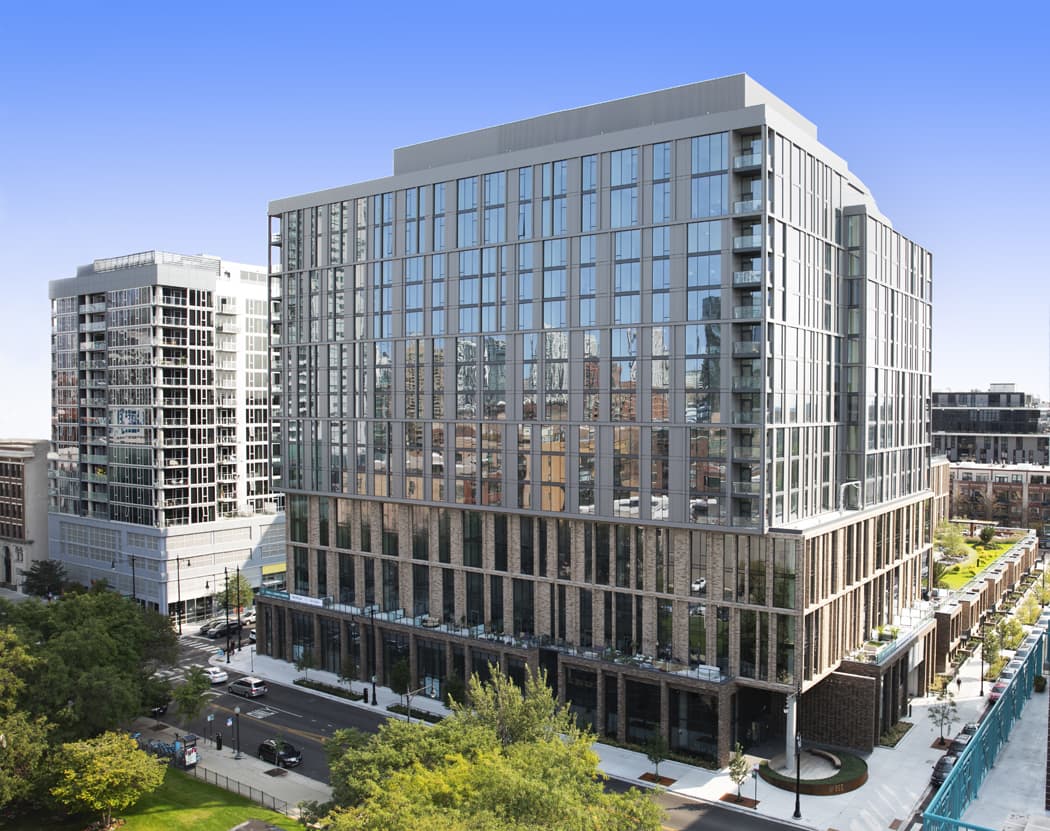 Modern apartment building with extensive glass facade, dark metal framing, ground-level retail, and surrounding urban streetscape in Chicago.