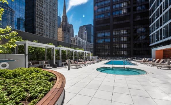 Rooftop pool deck with lounge chairs, pergola shade structures, and Chicago skyline backdrop.