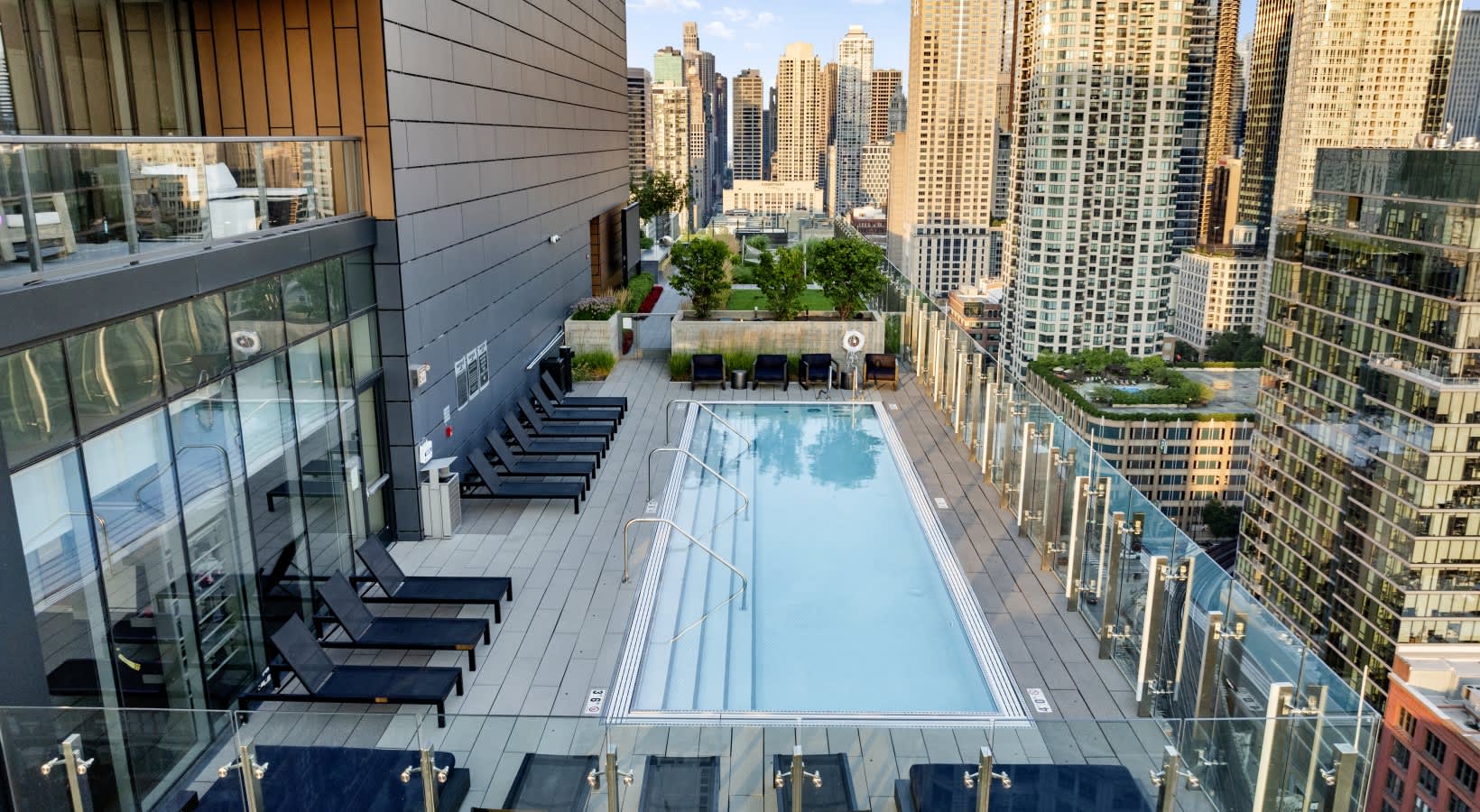 Rooftop pool with lounge chairs, planters, and Chicago skyline in background.