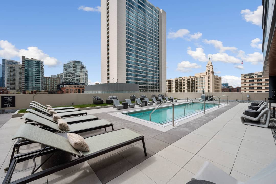 Rooftop pool deck with lounge chairs, heated pool, and Chicago downtown skyline backdrop.