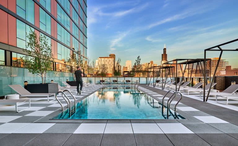 Rooftop pool with lounge chairs, pergola shade structures, and Chicago skyline in background.