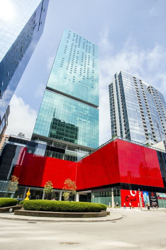 Three modern residential high-rise towers with glass and metal facades overlooking a red architectural structure and landscaped plaza in downtown Chicago.