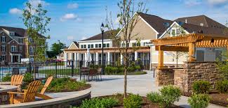 Exterior view of contemporary townhomes with brick and siding, wide patio areas, and mature landscaping in a residential community.