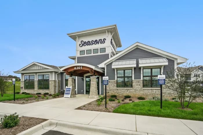 Modern residential building with gray siding, stone accents, large windows, and a central tower entrance marked 4301.