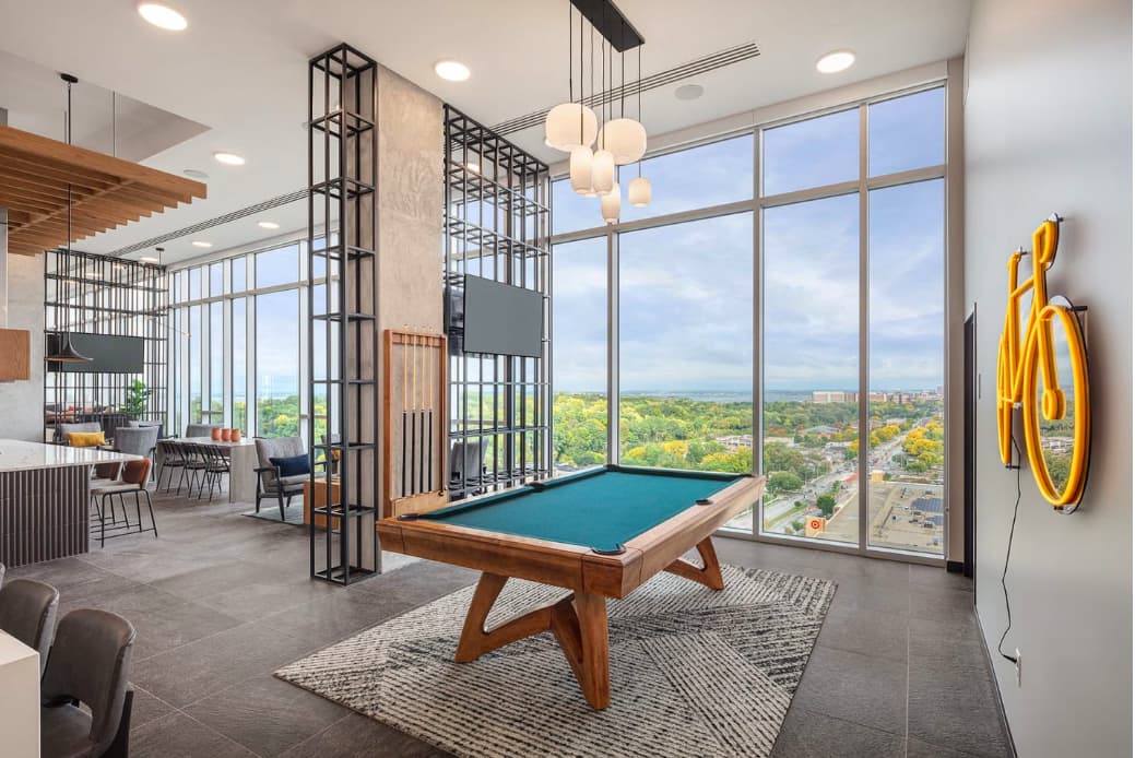High-rise game room with pool table, pendant lighting, floor-to-ceiling windows overlooking Madison cityscape and green landscape.