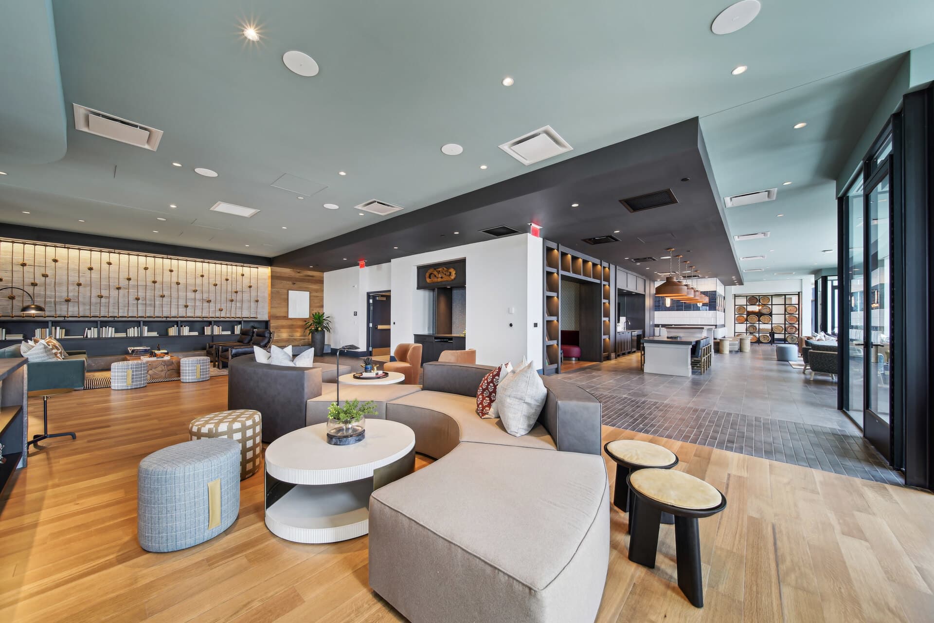 Open-concept common area with gray modular seating, round white coffee table, wood flooring, built-in shelving, and recessed ceiling lights.