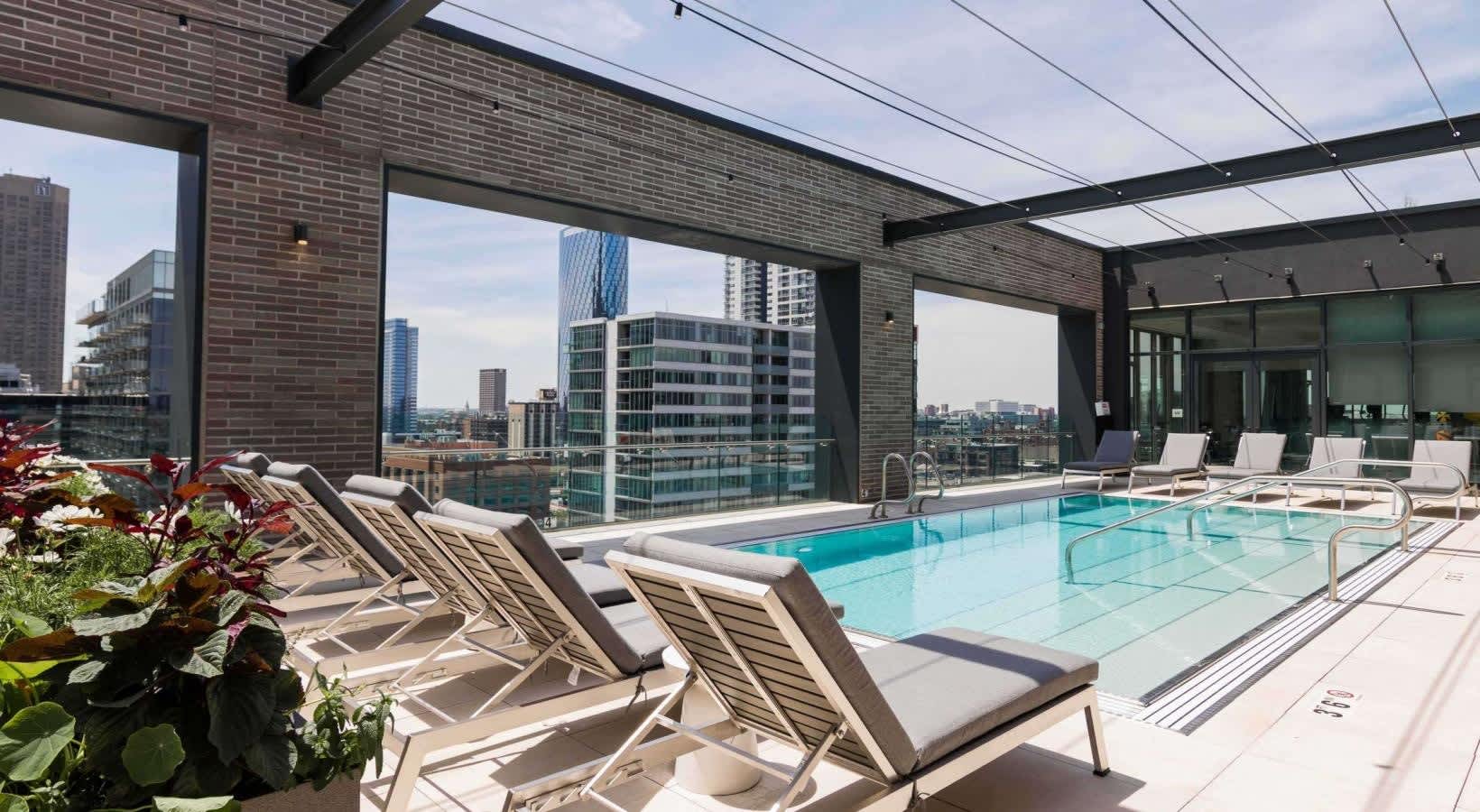 Rooftop pool with turquoise water, lounge chairs, and floor-to-ceiling windows framing downtown Chicago skyline.