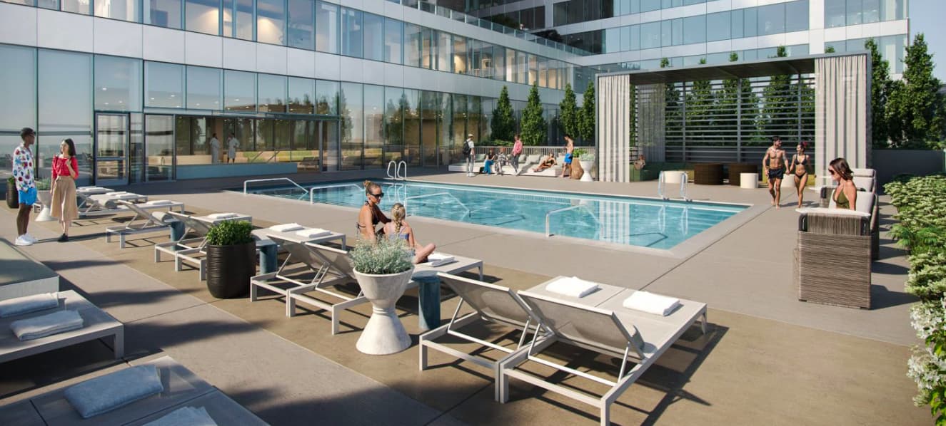 Rooftop pool deck with rectangular swimming pool, lounge chairs, planters, and residents relaxing in the sun near a modern glass building.