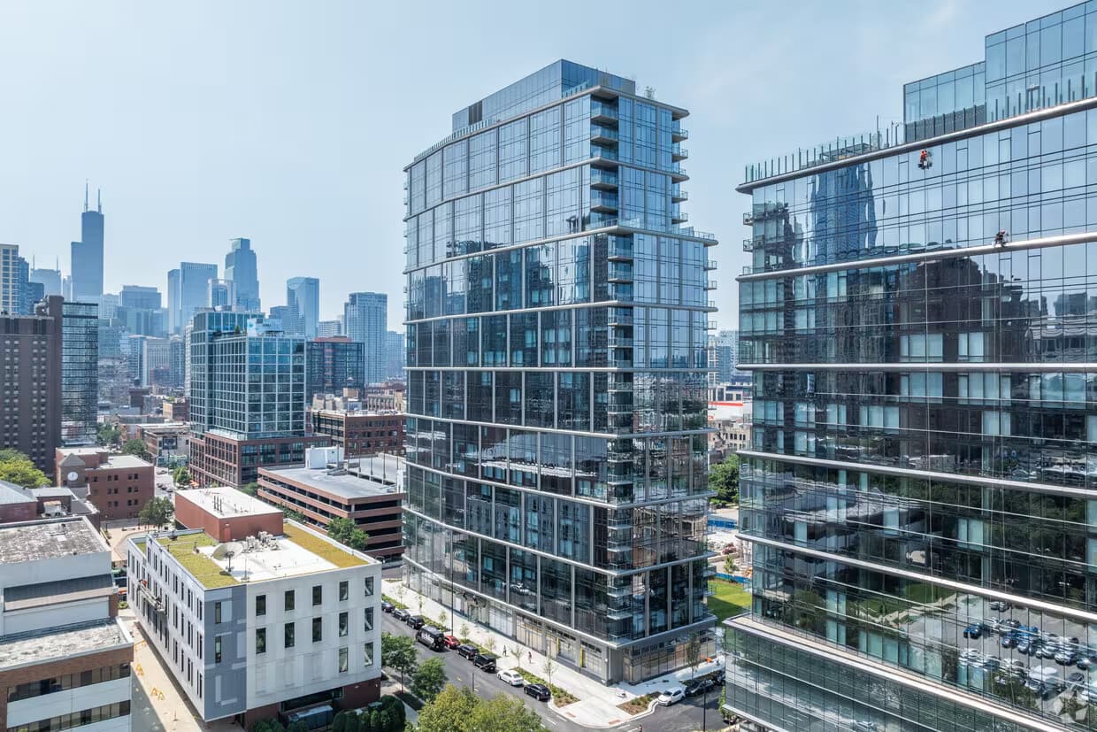Modern glass and steel high-rise residential tower in Chicago with floor-to-ceiling windows, surrounded by downtown buildings and skyline views.