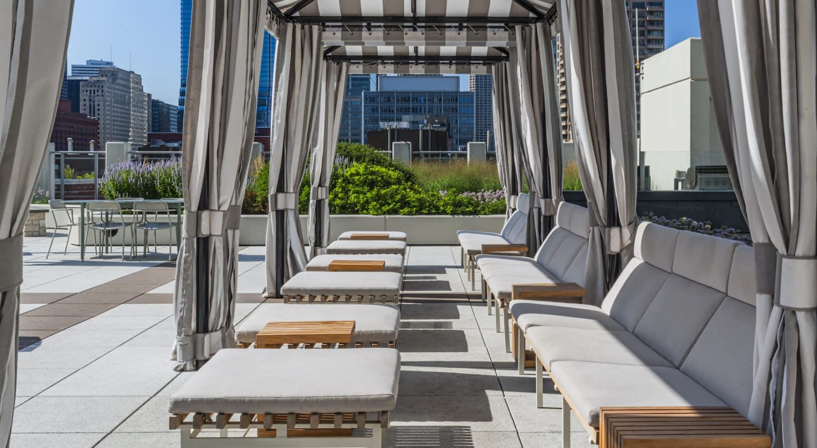 Rooftop lounge with striped cabanas, cushioned seating, and city skyline views in Chicago.