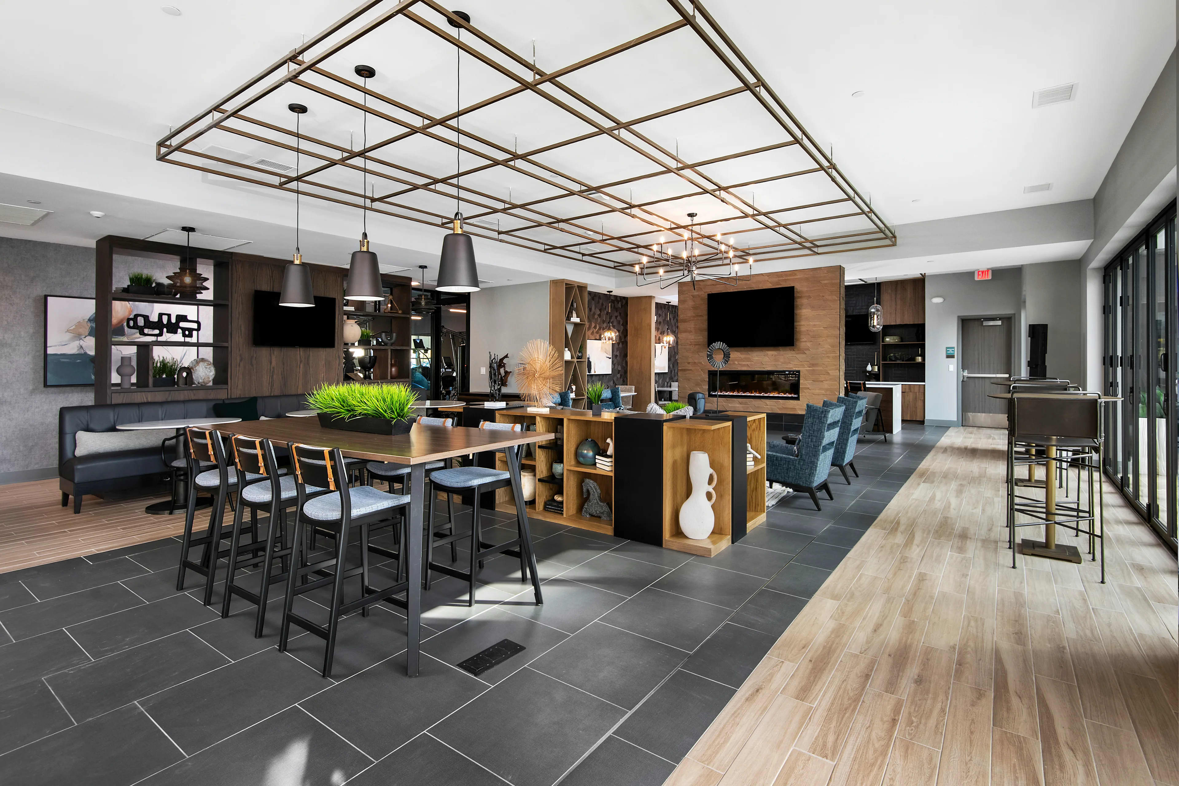 Open-concept common area with wood and black kitchen island, dining table with chairs, pendant lighting, fireplace, and gray tile flooring.