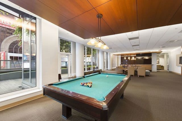Game room with turquoise pool table, wooden ceiling, pendant lighting, and large windows overlooking Broadway street.