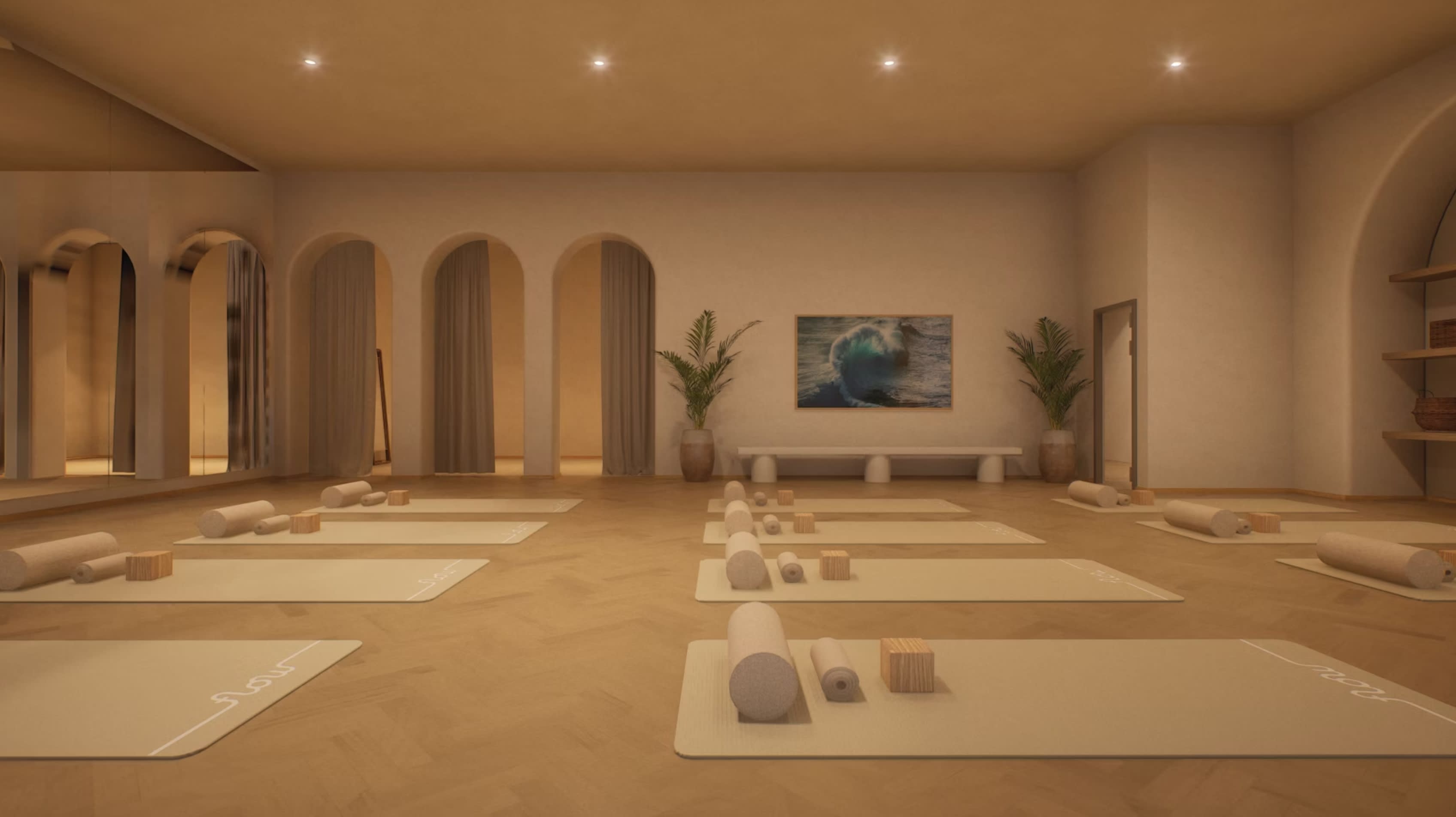 Yoga studio with multiple mats arranged on wood floor, arched wall niches with curtains, potted plants, and ocean artwork.