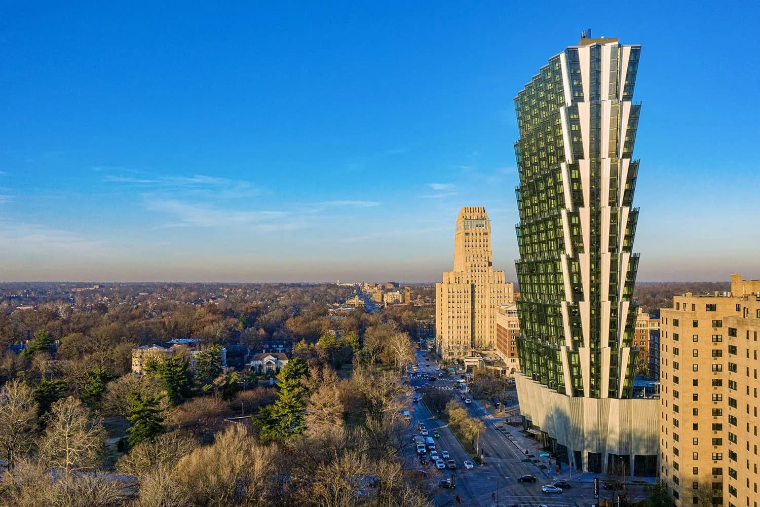 High-rise apartment building with green and white striped facade overlooking downtown St. Louis, historic buildings, and tree-lined neighborhoods under clear blue sky.
