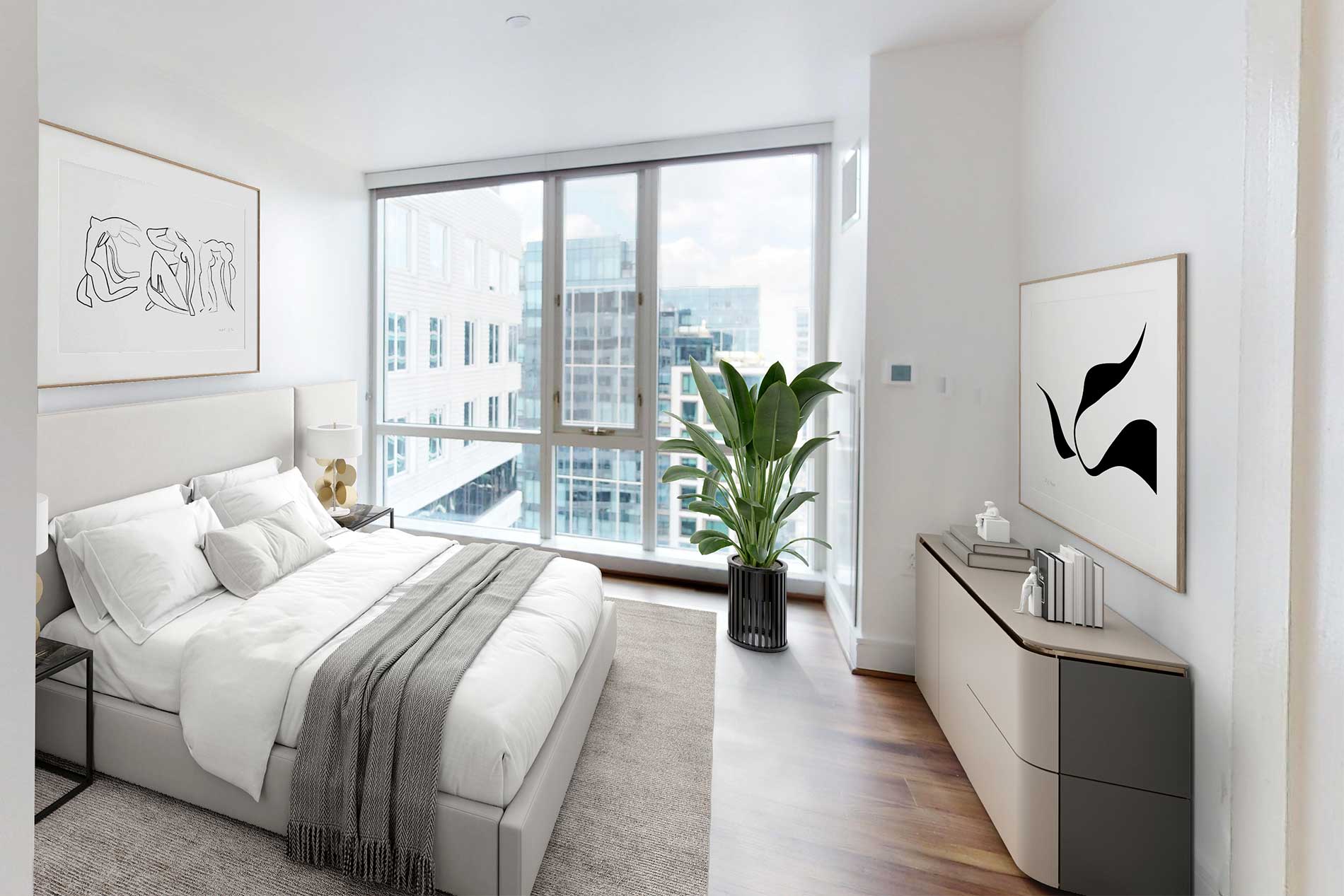 Bedroom with white upholstered bed, gray throw blanket, potted plant, framed line art, and expansive windows with city views.