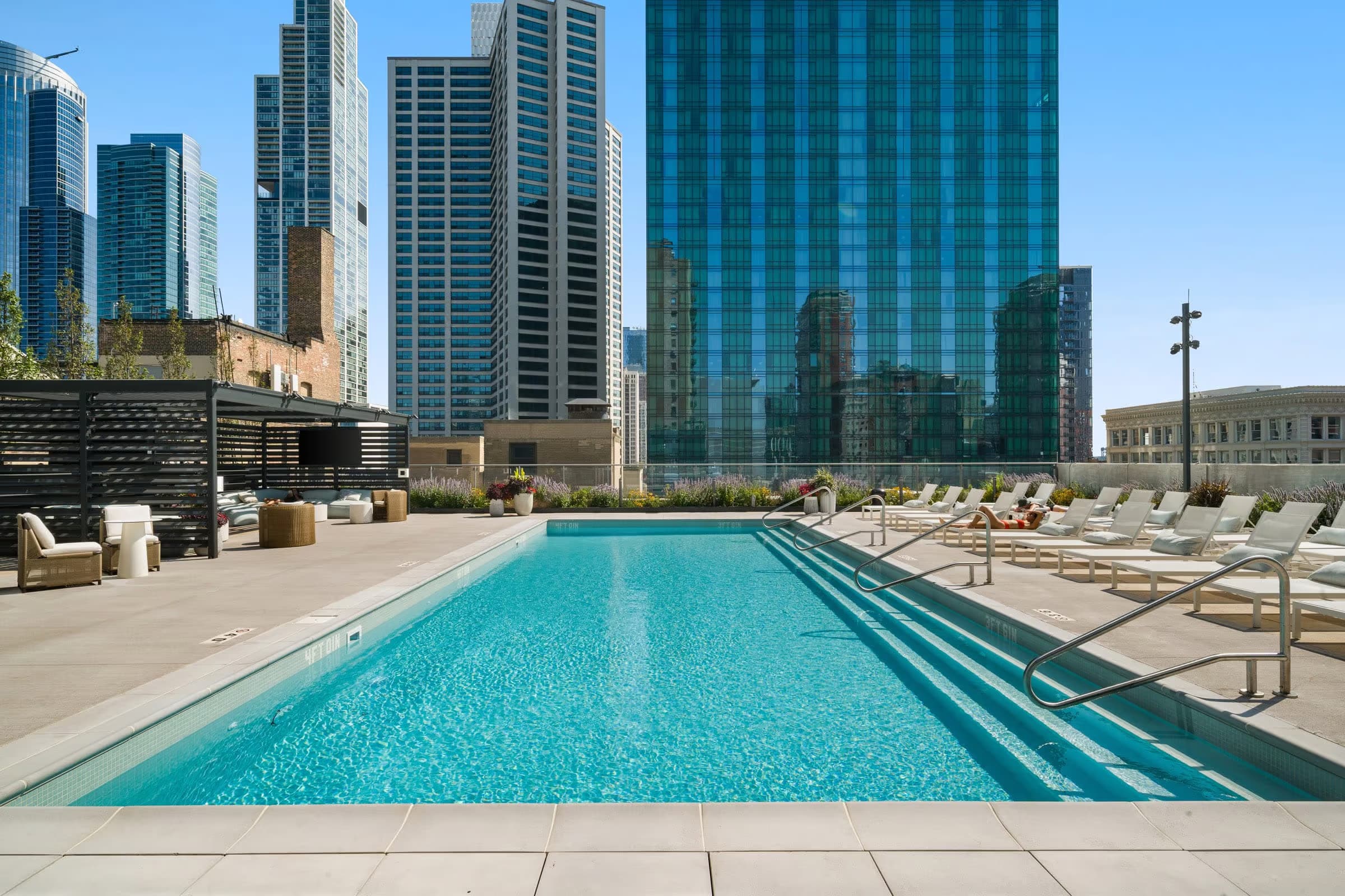 Rooftop swimming pool with turquoise water, lounge chairs, and downtown Chicago skyscrapers in background.