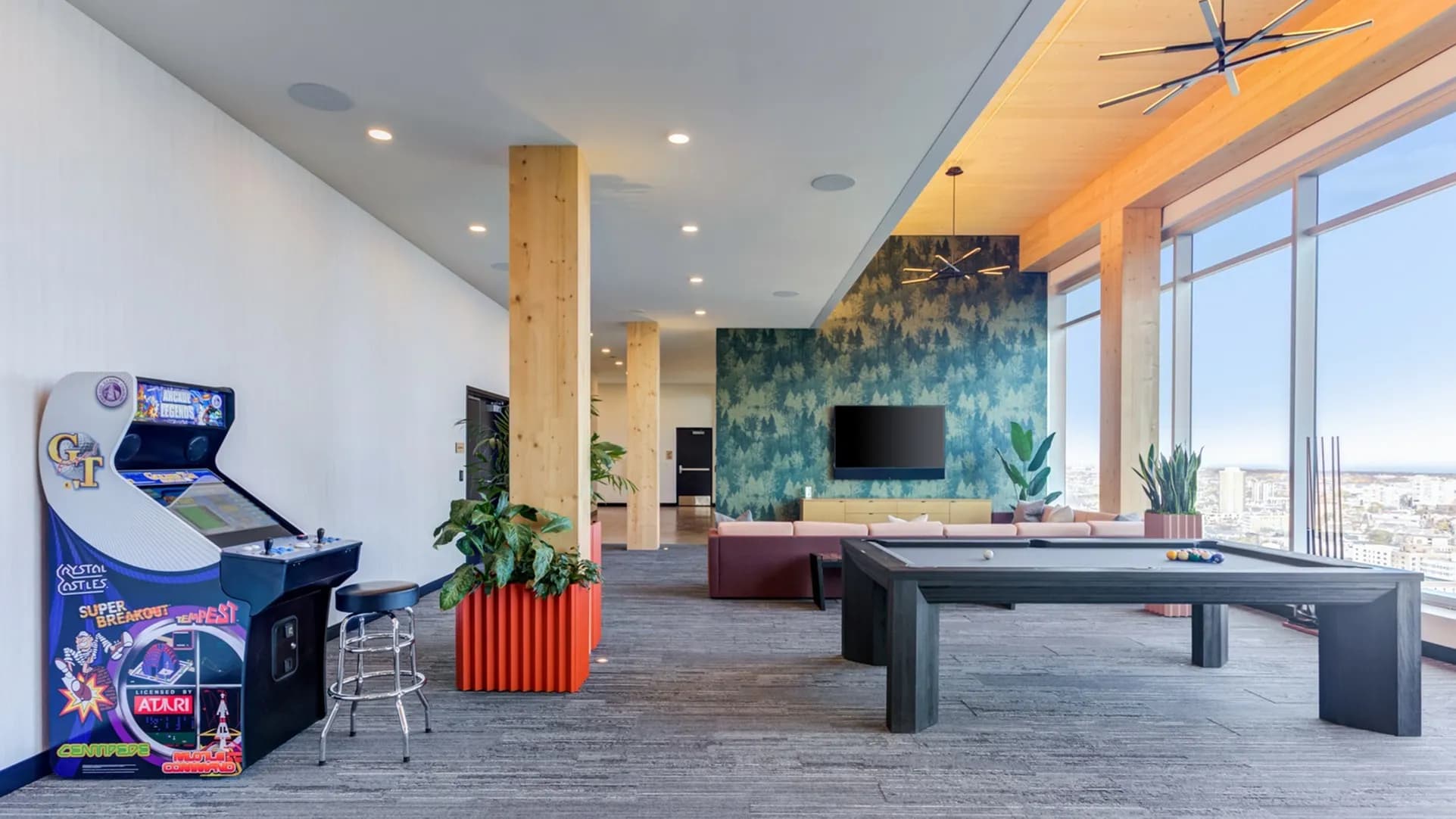 Recreation room with pool table, arcade game, potted plants, and expansive windows with city views.