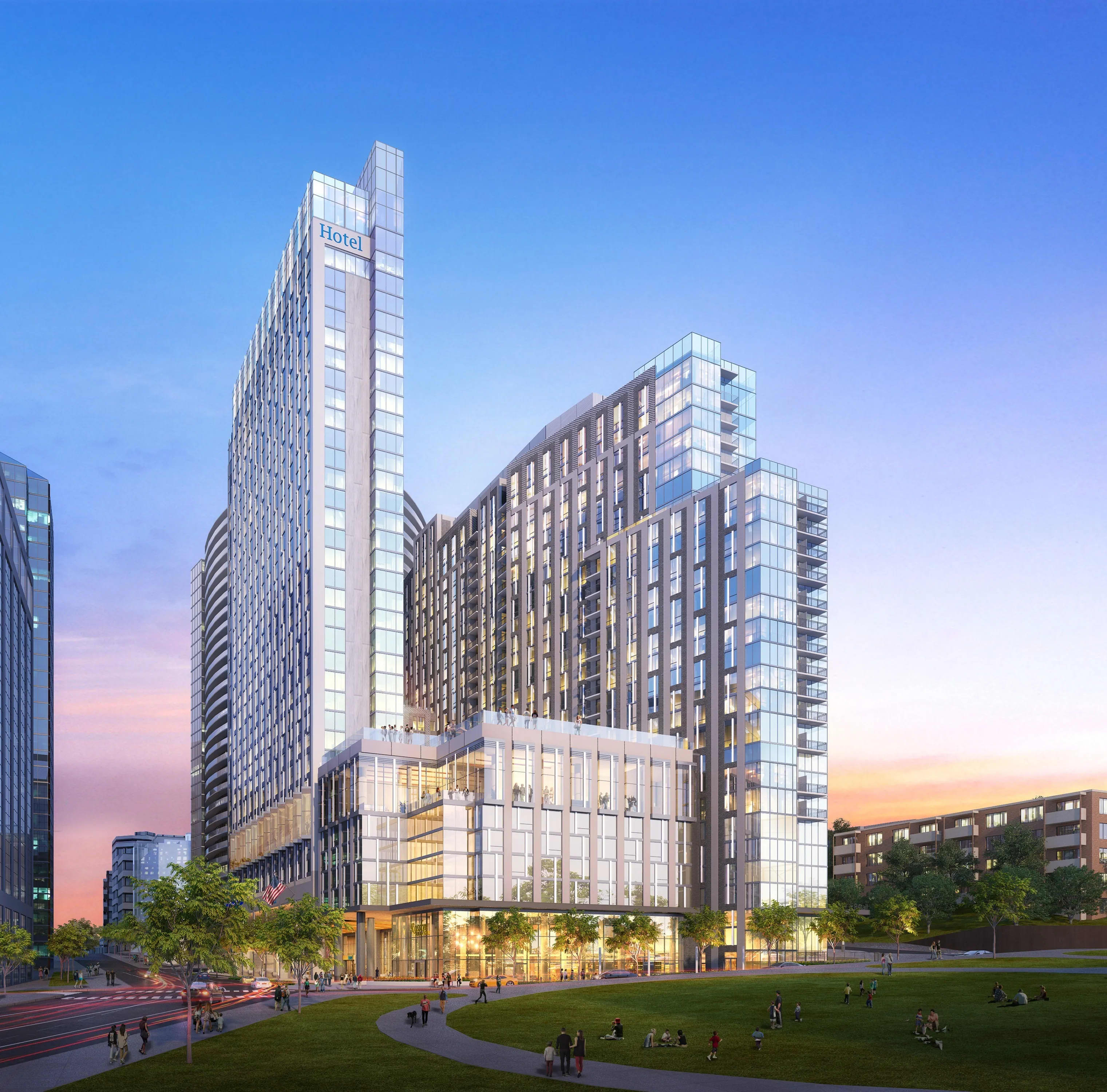Modern high-rise residential and hotel towers with glass and metal facades overlooking a green plaza with pedestrians at sunset.