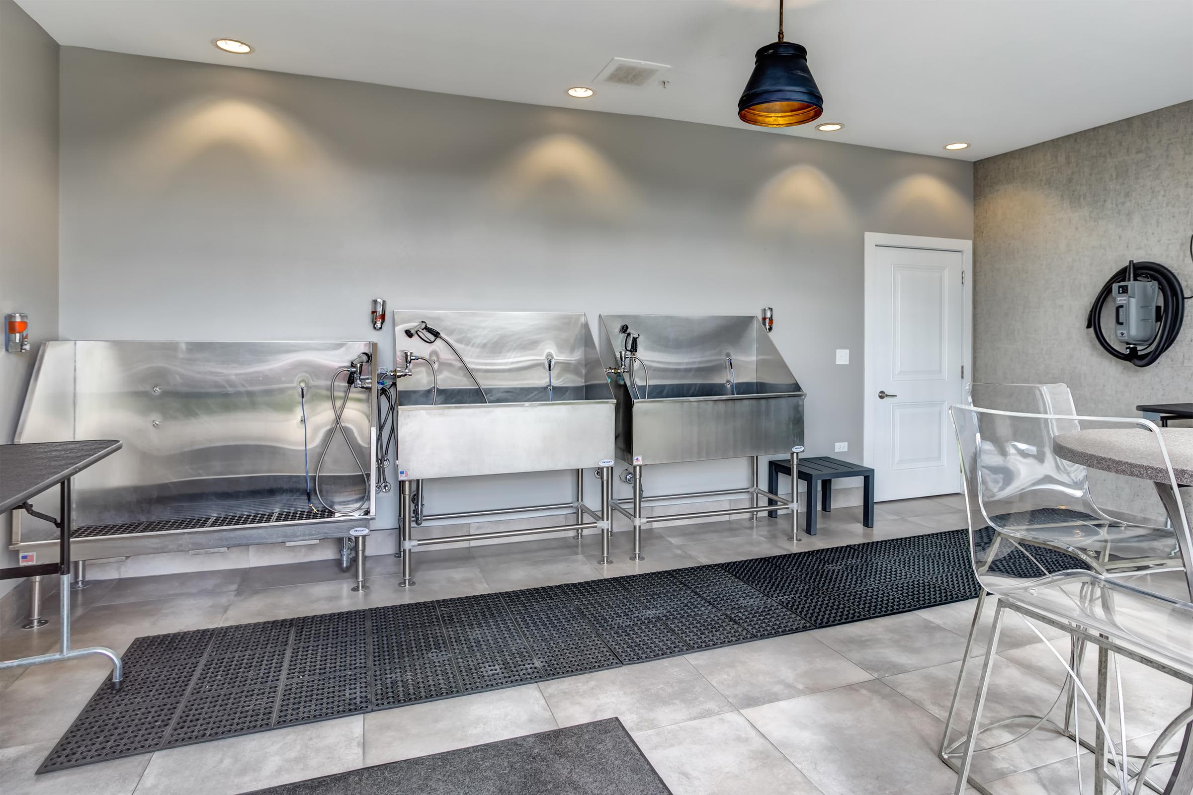 Fitness center with stainless steel exercise equipment, treadmills, recessed lighting, and black anti-fatigue flooring.