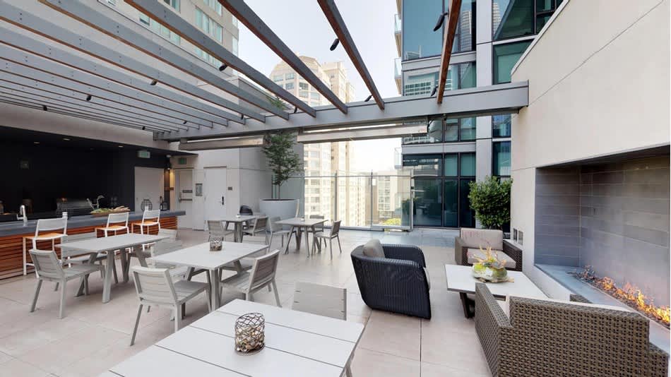 Rooftop terrace with dining tables, lounge seating, retractable shade pergola, and city views at 399 Fremont in San Francisco.