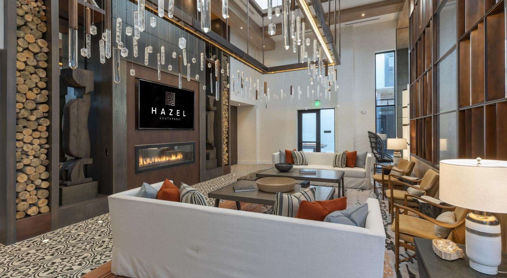 Contemporary living room with white sectional sofa, linear fireplace, hanging crystal pendant lights, and wood accent wall.