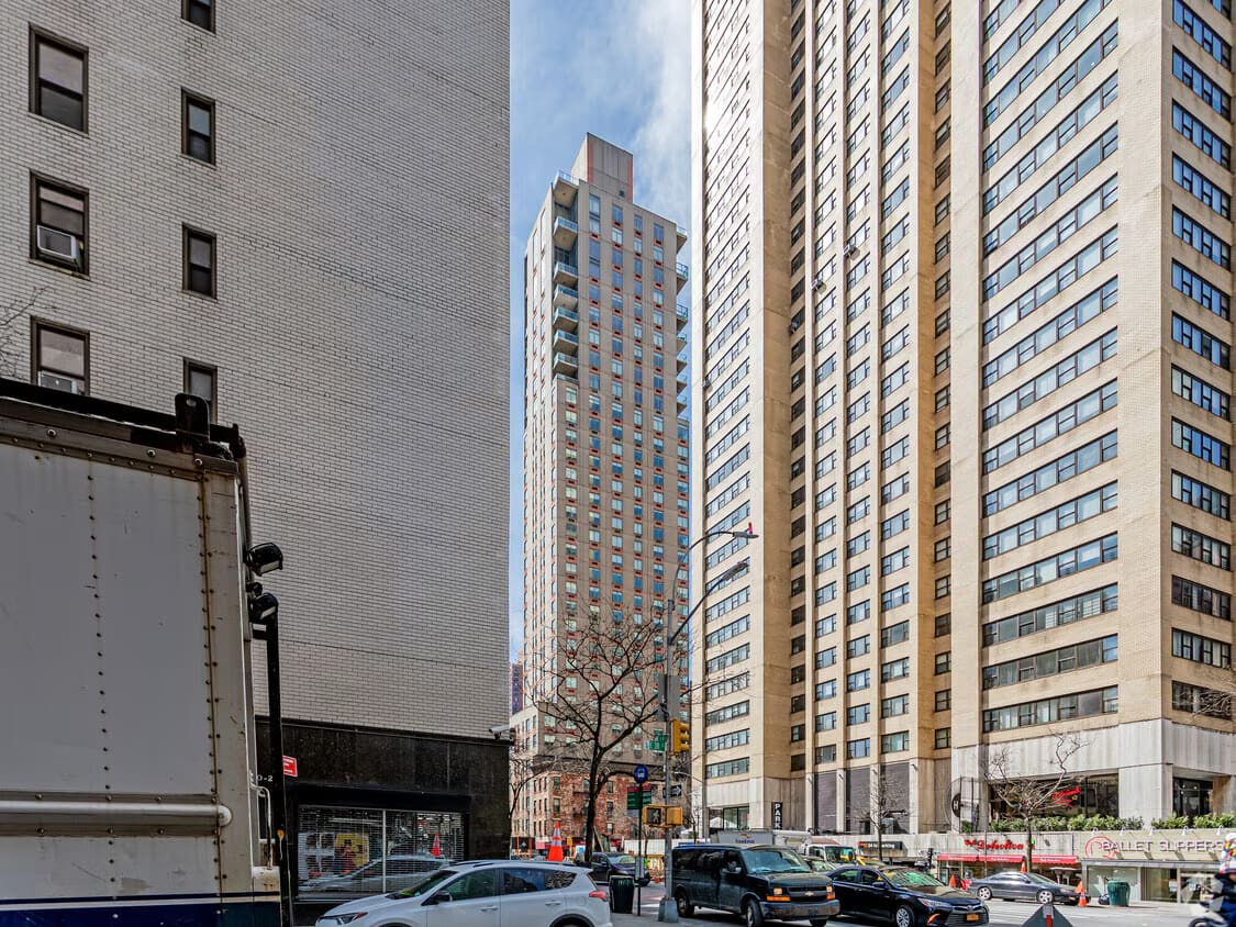 Street view of tall residential buildings on 3rd Avenue in Midtown Manhattan with parked cars and storefronts at ground level.