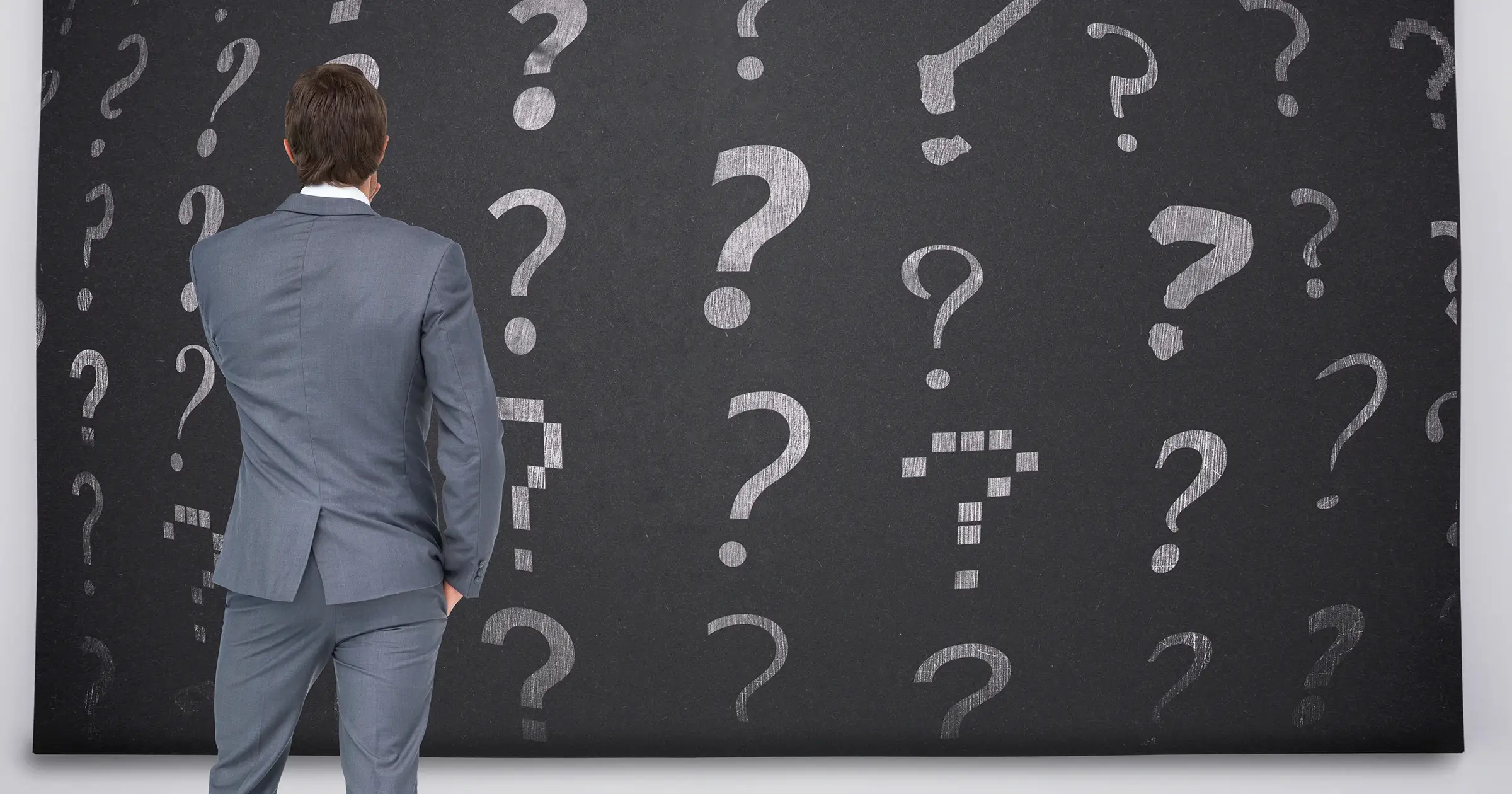 Man in front of a blackboard of questionmarks