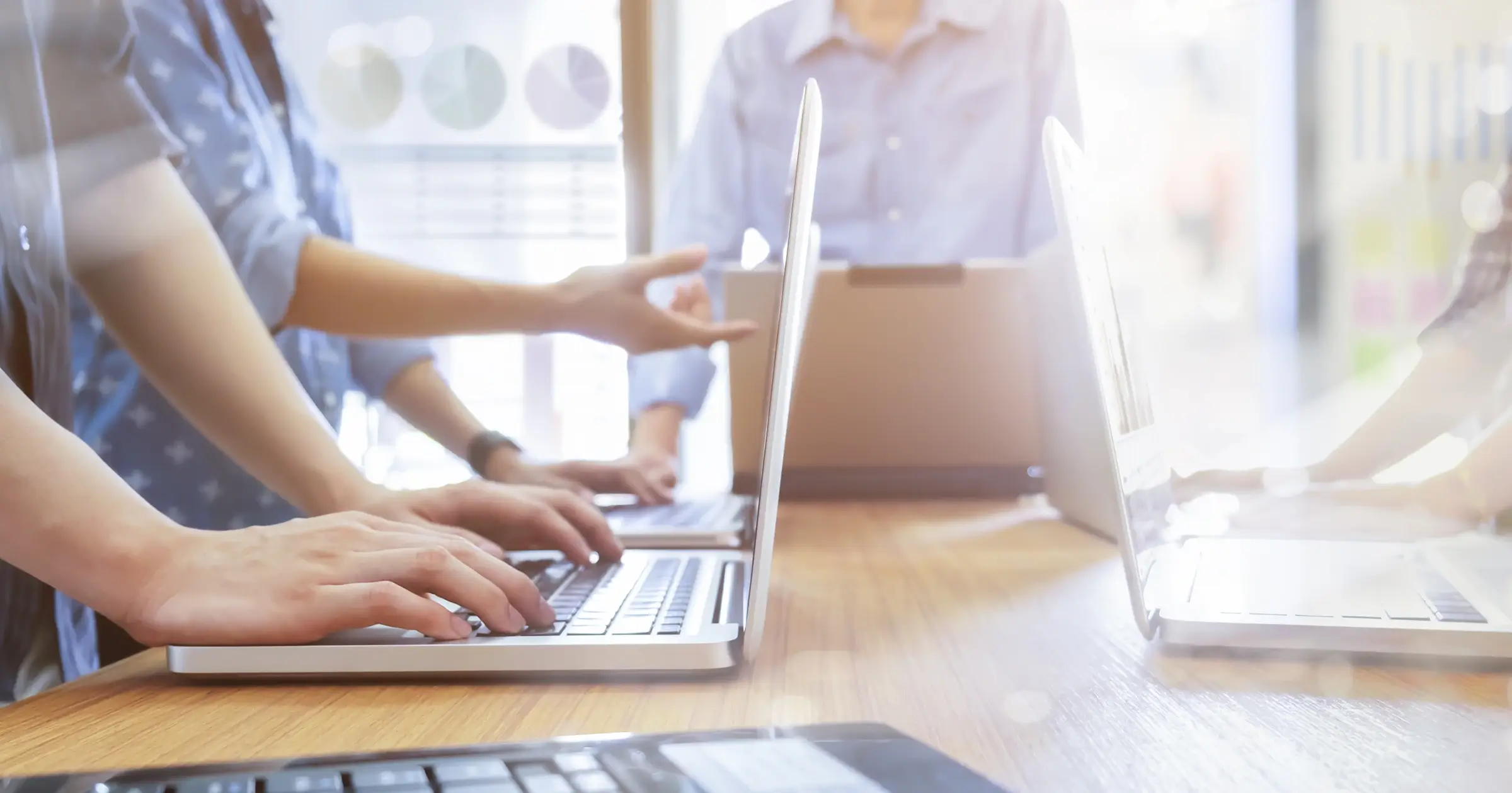 People with laptops standing around a high desk